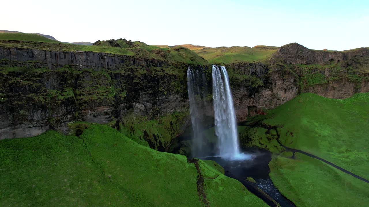 cascada artificial con colinas verdes en un día soleado en islandia