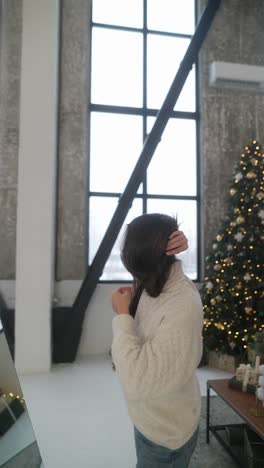 woman in a sweater by a christmas tree