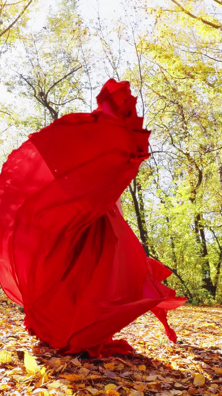 A Stunning Display of Elegance: A Model in a Flowing Red Dress Captivatingly Poses Underneath Dappled Autumn Light Surrounded by Vibrant Golden Leaves