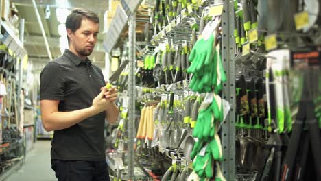man shopping for gardening tools in a hardware store