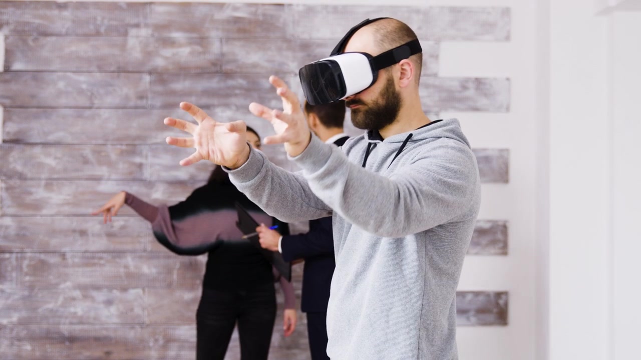 Uomo che testa un visore per realtà virtuale in ufficio con i colleghi