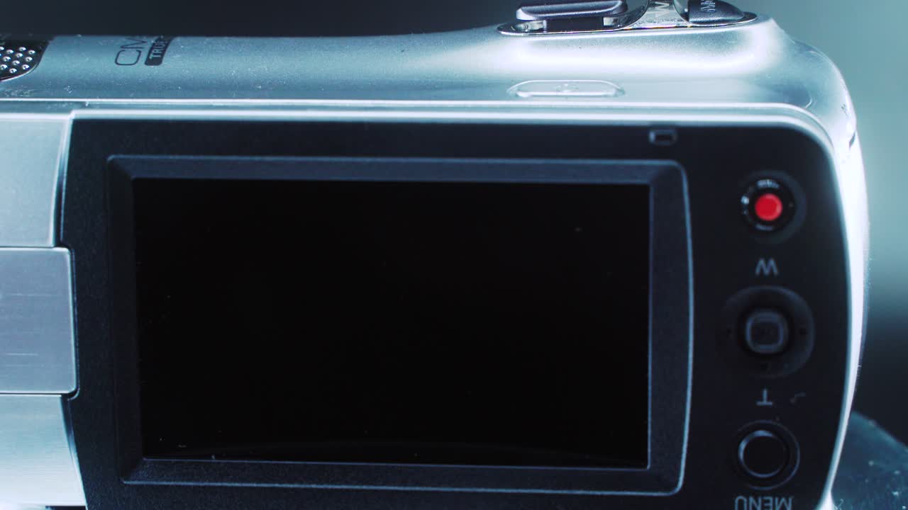 비디오 카메라의 클로즈업 샷, 360도 회전 스탠드의 은색 캠코더, 스튜디오 조명, 느린 동작 4k 비디오, 뒤집힌 화면, 레코드 및 메뉴 버튼