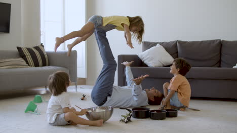 Father-holding-daughter-on-legs-and-lying-on-carpet