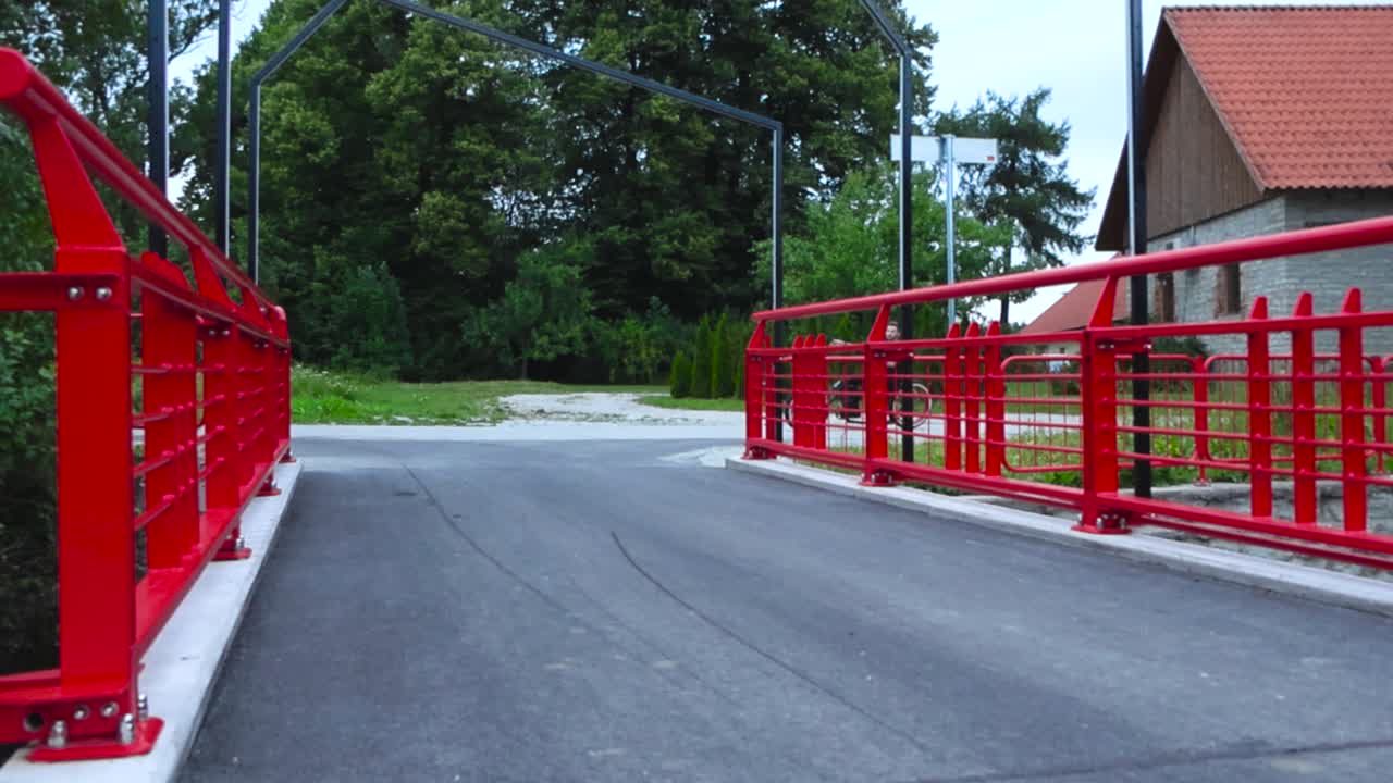Cyclist riding on a bridge with red railings