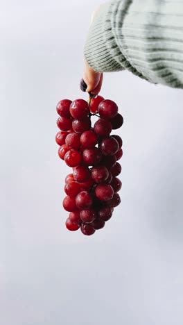 hand holding a bunch of red grapes