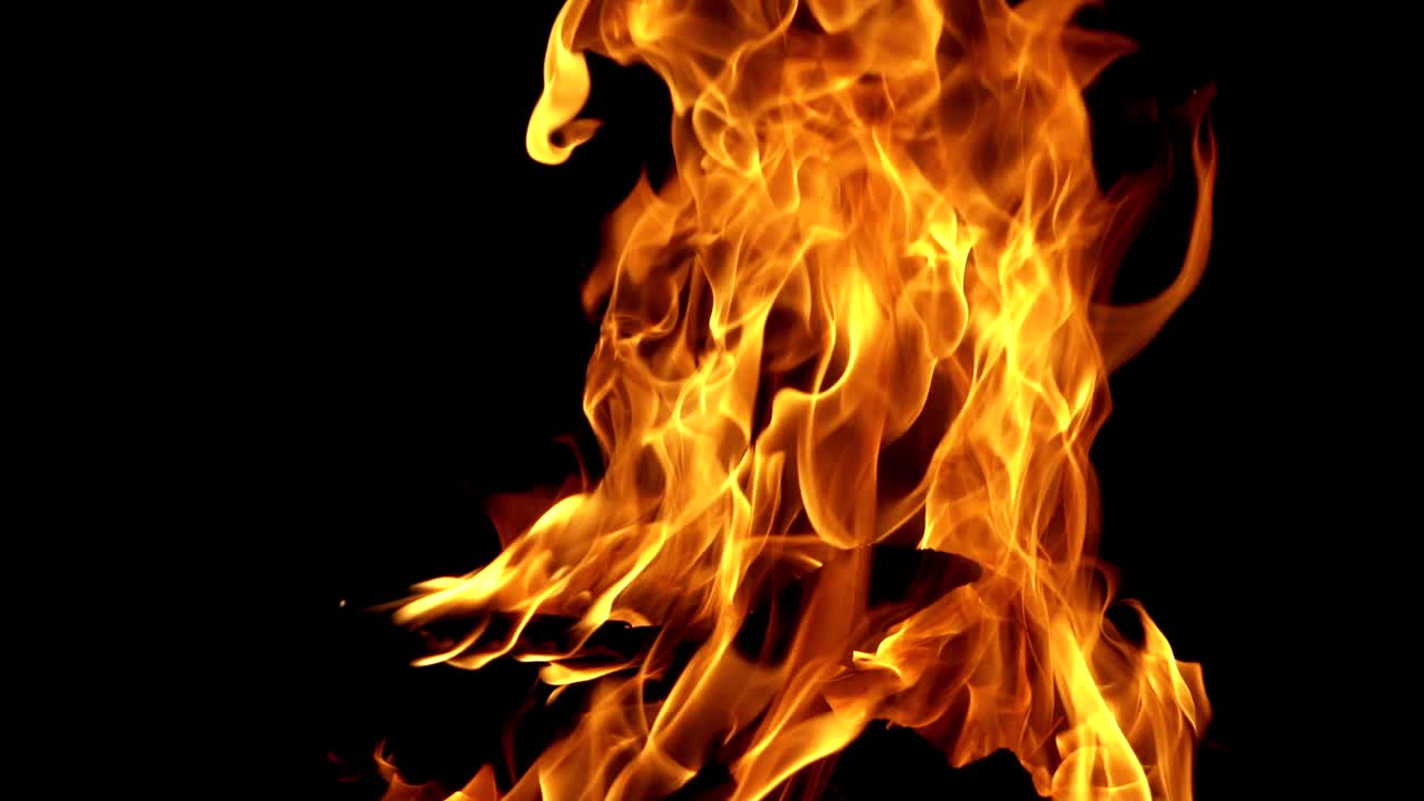 Burning bright camping fire on black background at night. Slow motion shot of fire sparks moving on dark. Close-up