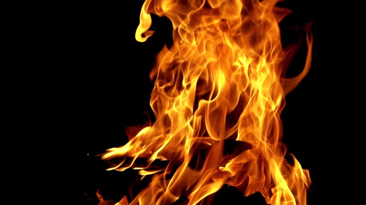 Burning bright camping fire on black background at night. Slow motion shot of fire sparks moving on dark. Close-up
