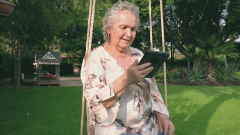 woman with gray hair sitting outside and reading electronic book