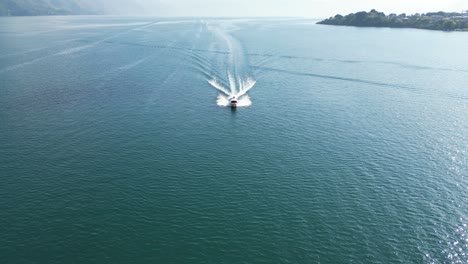 vista de avión no tripulado en guatemala volando cerca sobre un barco en un lago azul con montañas verdes en el lado en un día soleado en aitlan