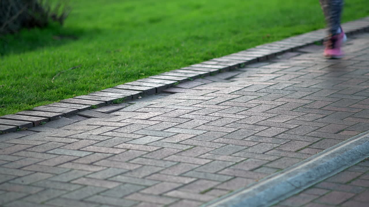 People running at the park. Focus on a lamp post base with feet running out of focus. King George's Park, London