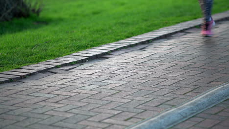 people running at the park. focus on a lamp post base with feet running out of focus. king george's park, london