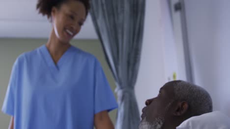 african american male patient in hospital bed talking with mixed race female doctor