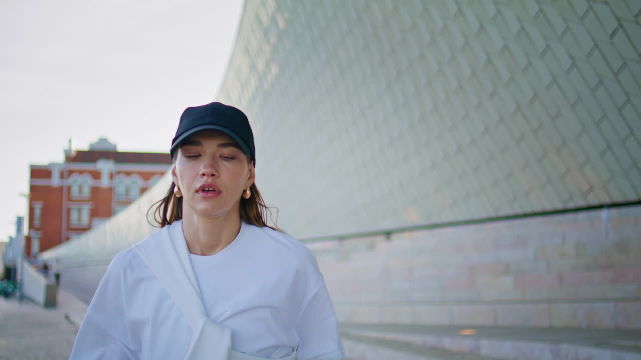 Sporty woman start running urban street wearing cap closeup. Brunette jogging