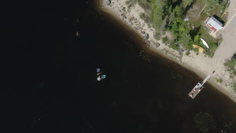 Top-view-drone-shot-of-young-people-swimming-in-a-river-in-Sweden