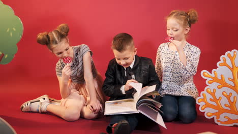 curious children reading book together. happy childhood. studio shooting of children