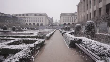 slowly moving forward in the beautiful mont des arts gardens in brussels, belgium during snowfall - pov tracking shot
