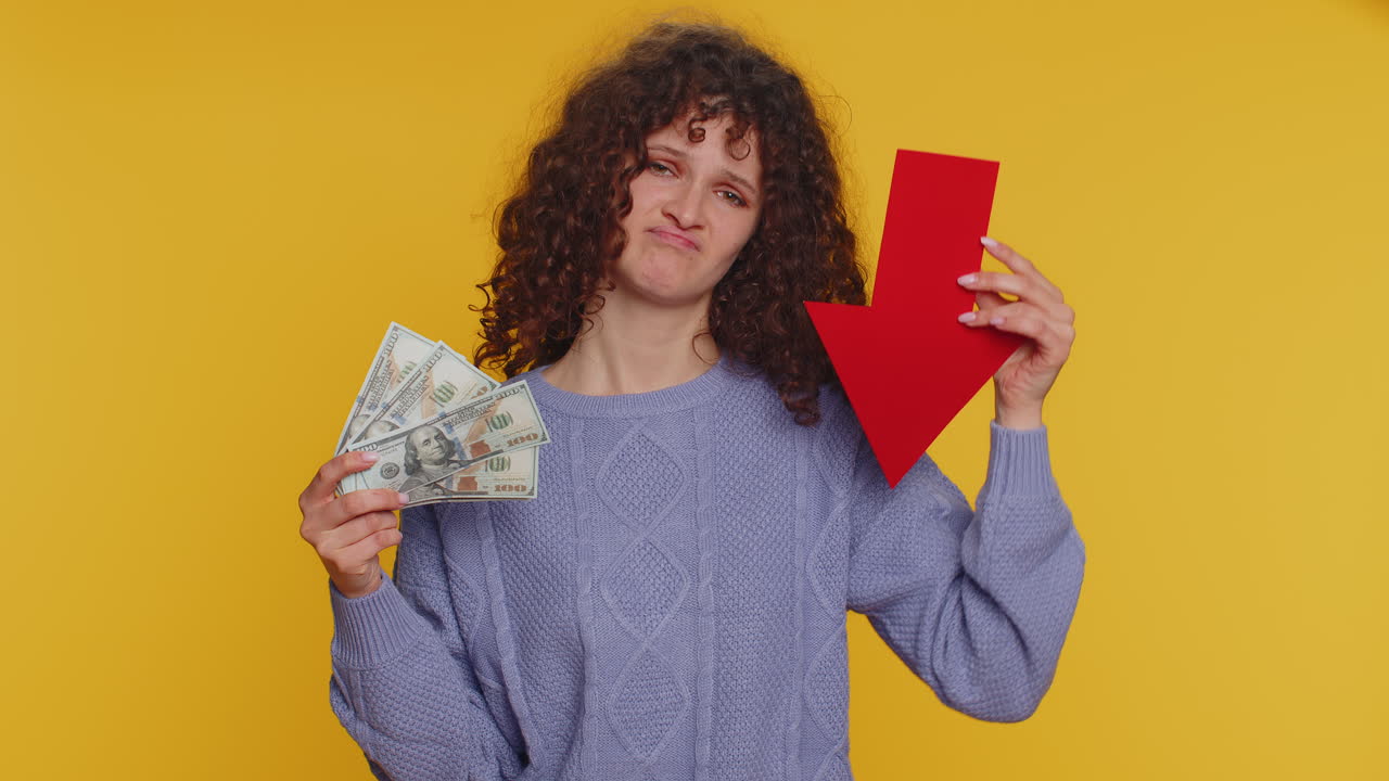 mujer molesta mostrando flecha roja apuntando hacia abajo, concepto de rebaja de la bancarrota dinero dólar fracaso, caída