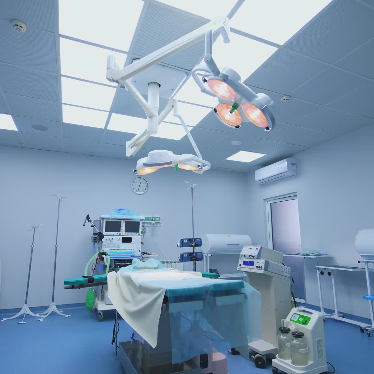 Modern medical equipment in empty surgical room. Sterile operating theatre ready for operation in hospital. Bright lamp over the surgical table