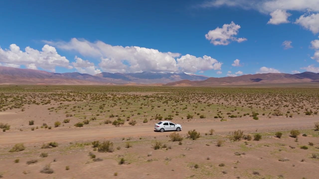 Drone che traccia un'auto bianca attraverso il deserto vicino alle dune di sabbia di Corralitos, vista aerea