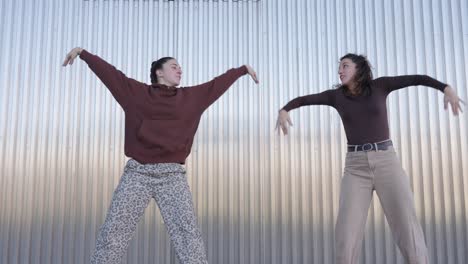 young woman dancing hip hop in front of metal wall
