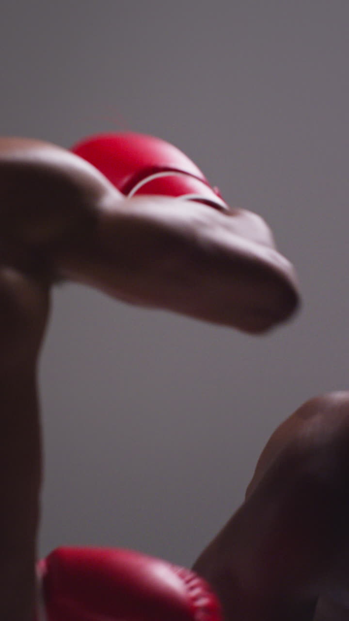 video vertical de primer plano de estudio de dos boxeadores masculinos con guantes luchando en un partido de boxeo 1