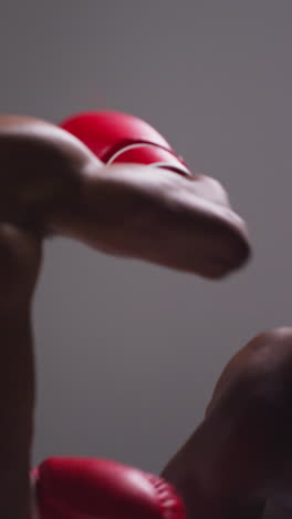 Vertical-Video-Close-Up-Studio-Shot-Of-Two-Male-Boxers-Wearing-Gloves-Fighting-In-Boxing-Match-1