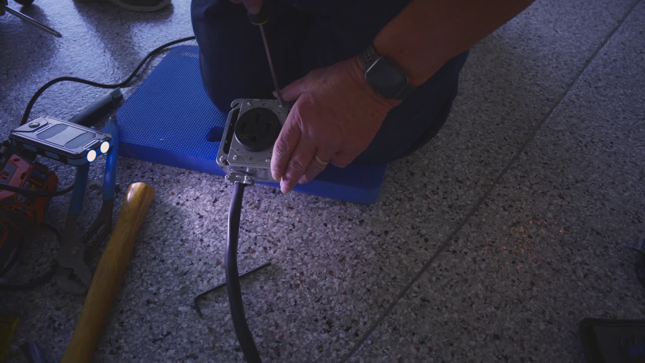 large hands assemble a high voltage electrical box for an electric vehicle EV charging station at home