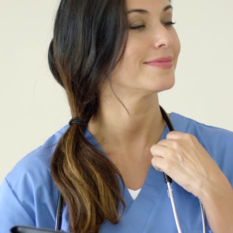 woman in scrubs holds black portfolio and smiles