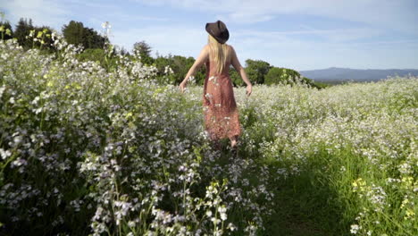 Slomo-Einer-Jungen-Frau,-Die-Durch-Ein-Blumenfeld-Hüpft