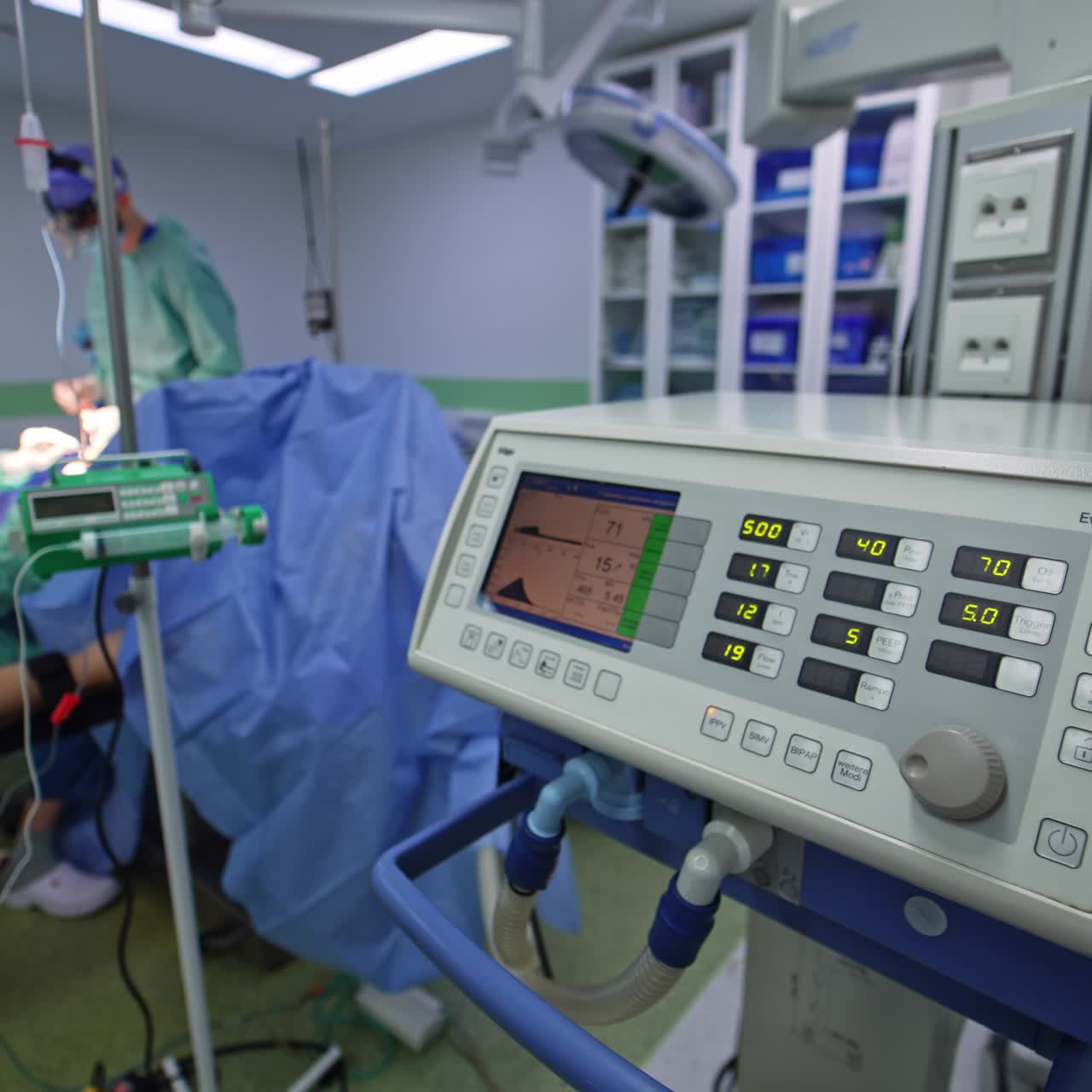 Diverse medical equipment working in the modern surgery room. Group of medics operating the patient at backdrop