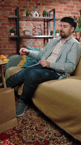 man relaxing at home and eating a snack