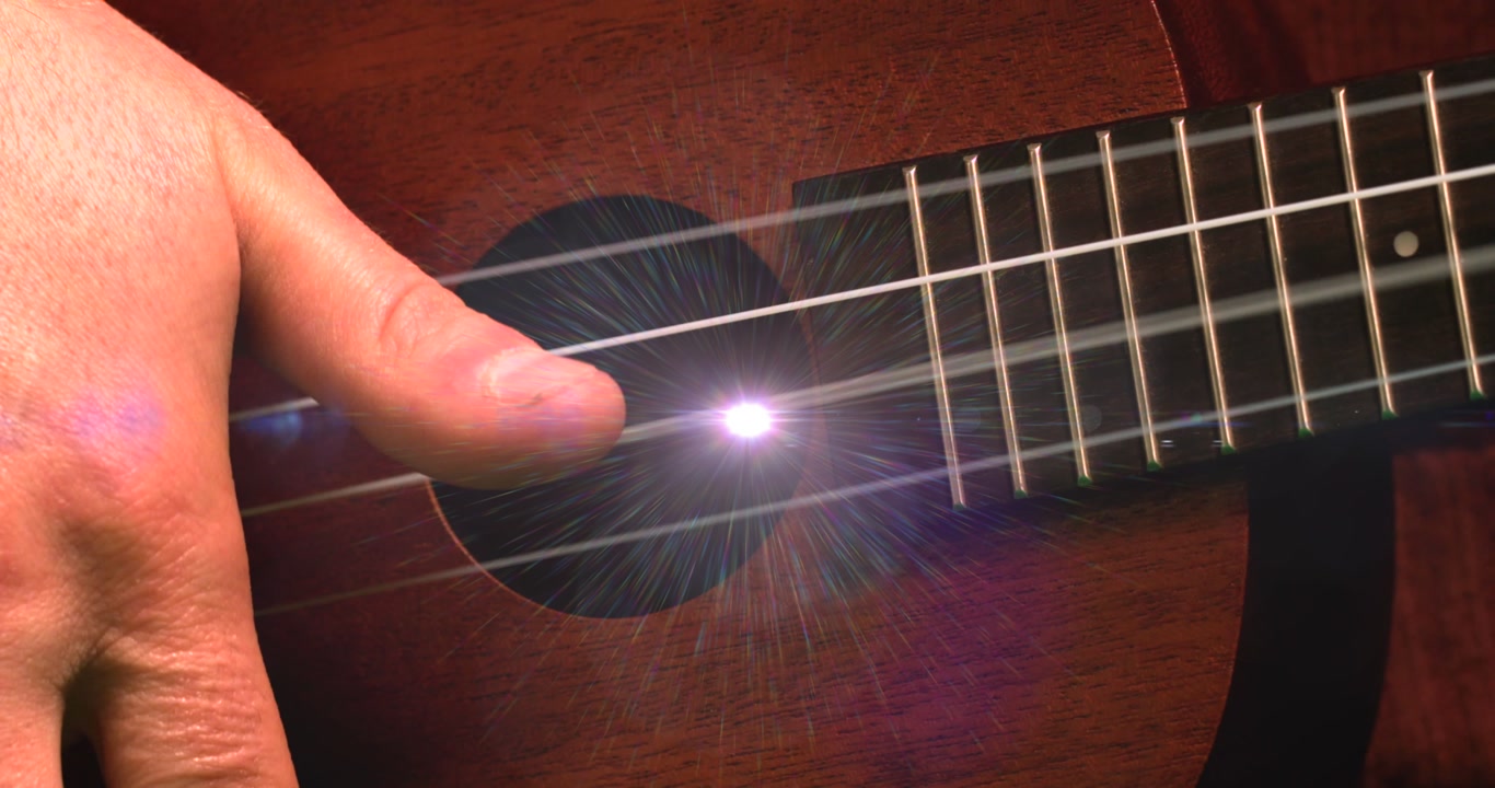 Animation of light flashing over hand of caucasian man playing guitar