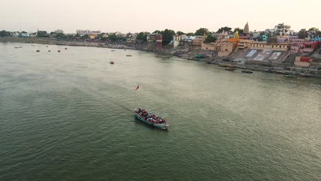 drone shot of banaras at dusk, with the ganga river shimmering under the setting sun and temple lights.