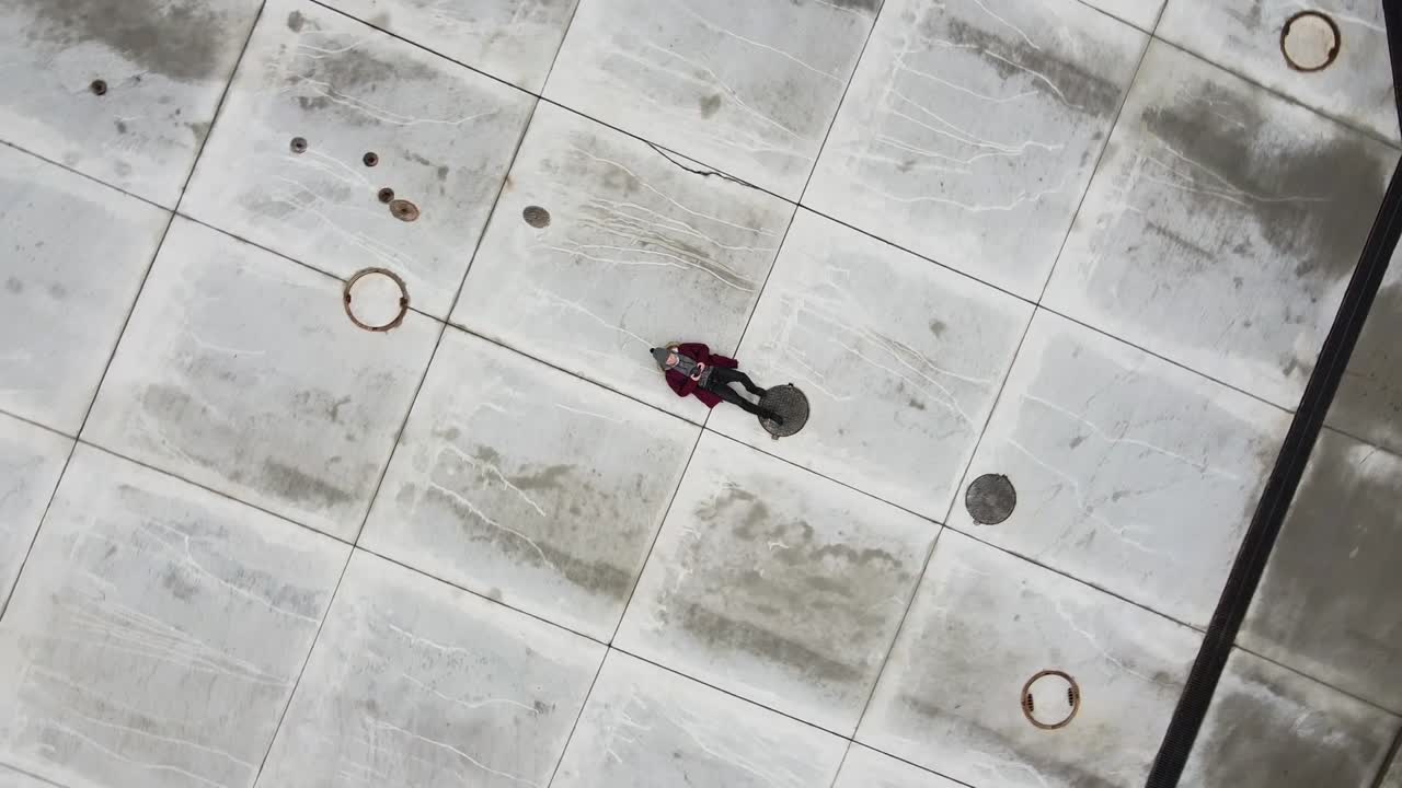 Lonely man laying on cold concrete ground empty road vertigo drone effect zoom out small earth