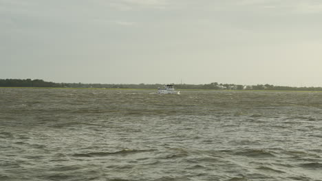 boat travels along the water at sunset, wide shot, static