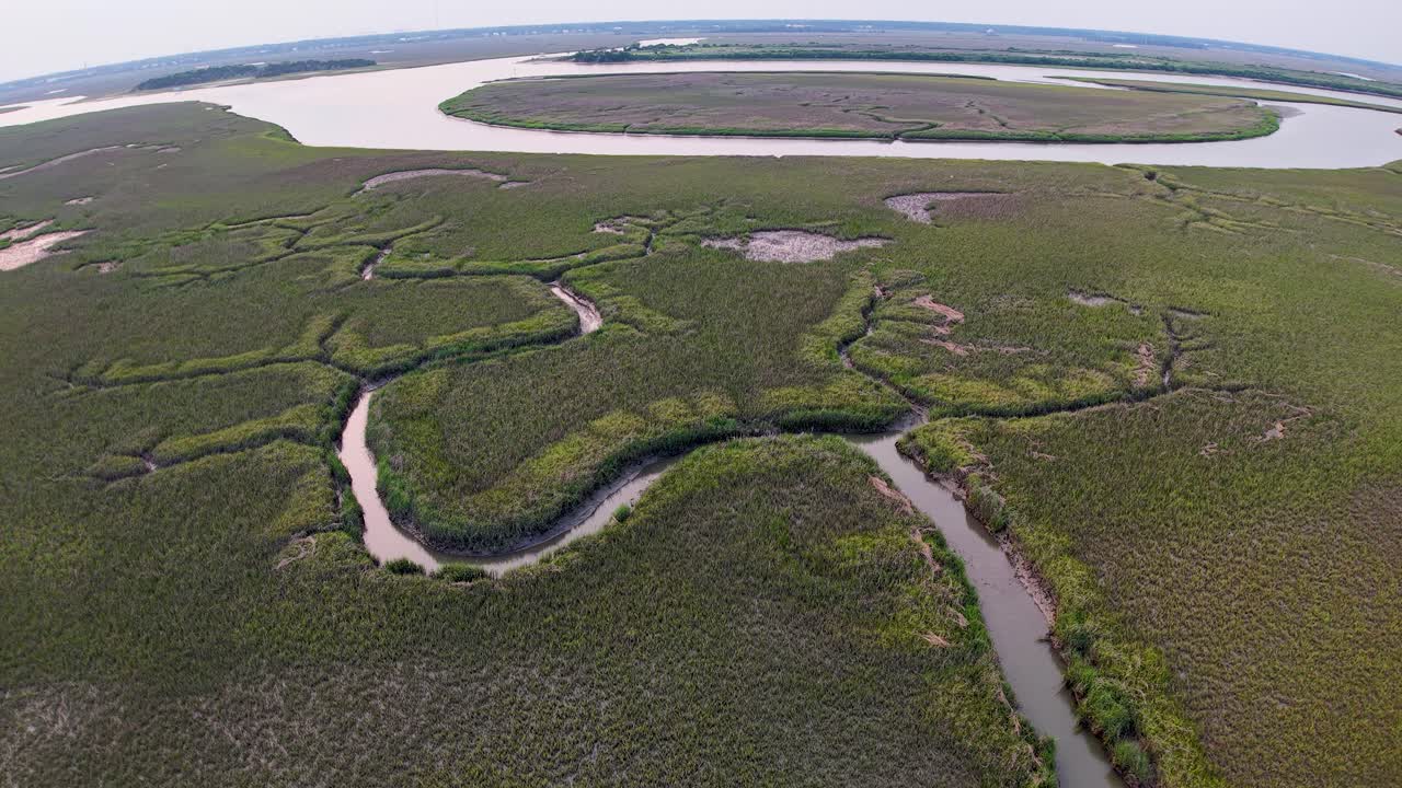 Drone footage displays sweeping marshlands in South Carolina with looping tidal channels and wetlands stretching toward the horizon