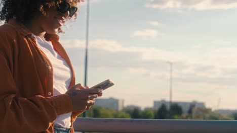 Black-woman-walking-across-the-bridge-and-looking-at-her-mobile-phone