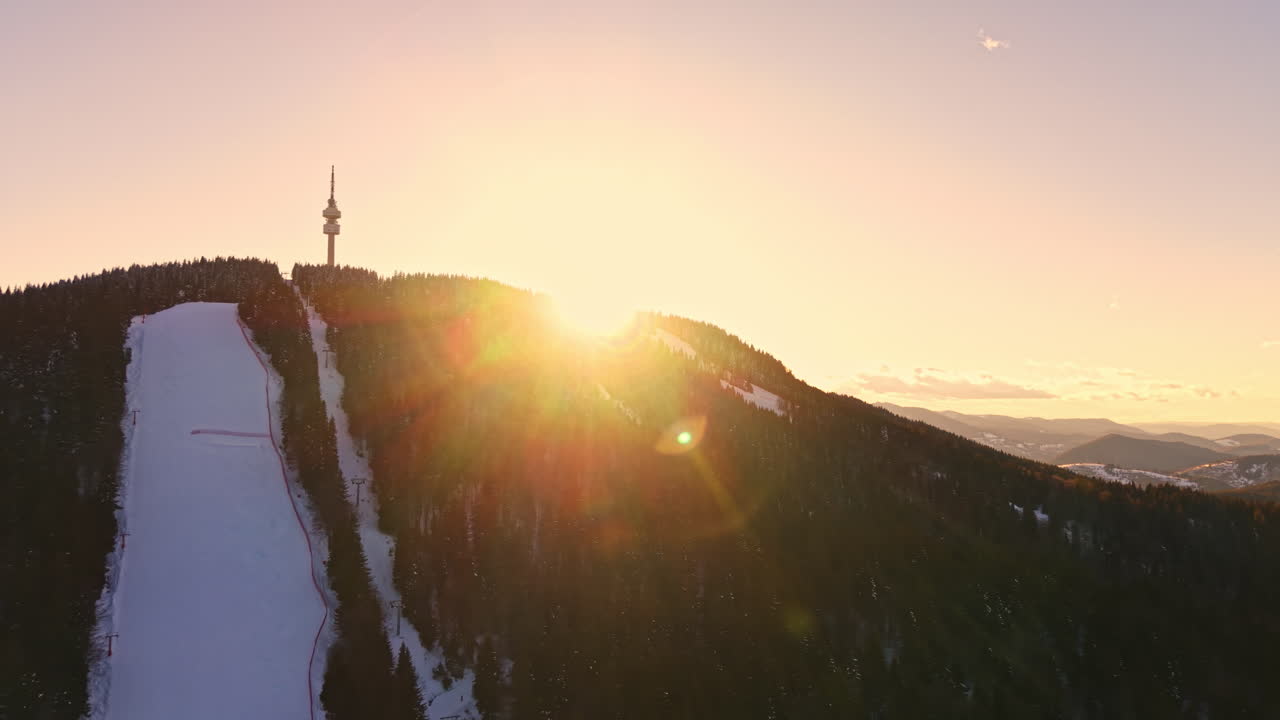 Alba su una montagna innevata con una torre di telecomunicazioni sulla cima e cielo sereno sullo sfondo