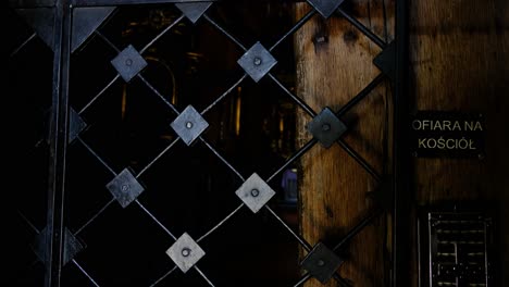 View-of-altar-and-cross-of-Christ-through-cast-iron-gate-of-famous-wooden-Polish-church-on-St