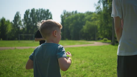 close-up of a family engaging in outdoor exercise on a grassy field, featuring a young child, a teenage boy, and their grandfather jumping, with a blurred goal post visible behind