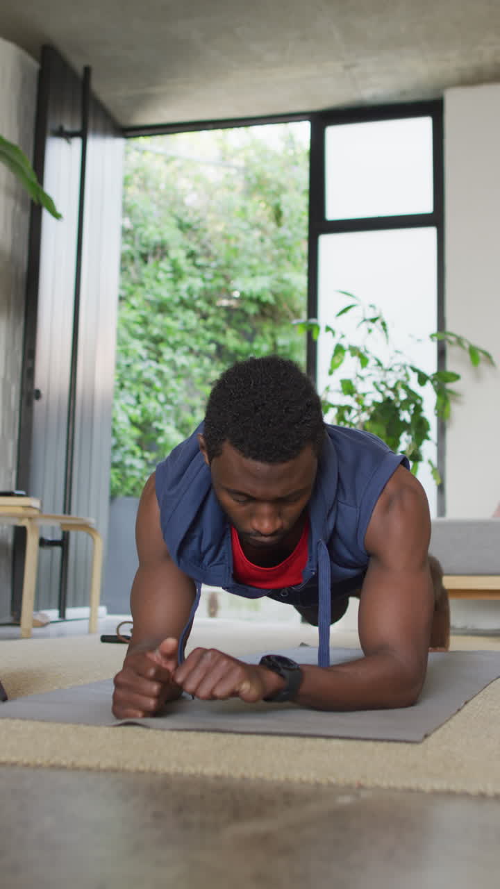 video vertical de un hombre afroamericano haciendo ejercicio en la sala de estar