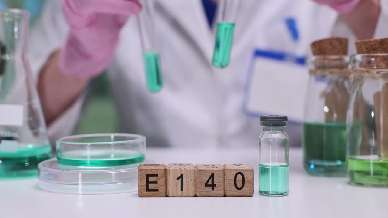 Scienziato che esamina l'additivo alimentare E140 con liquidi verdi in laboratorio