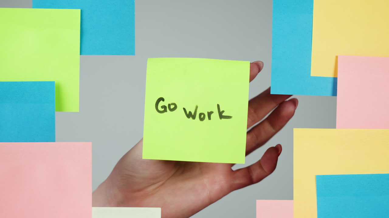 Hand Placing 'Go Work' Sticky Note on Grey Background