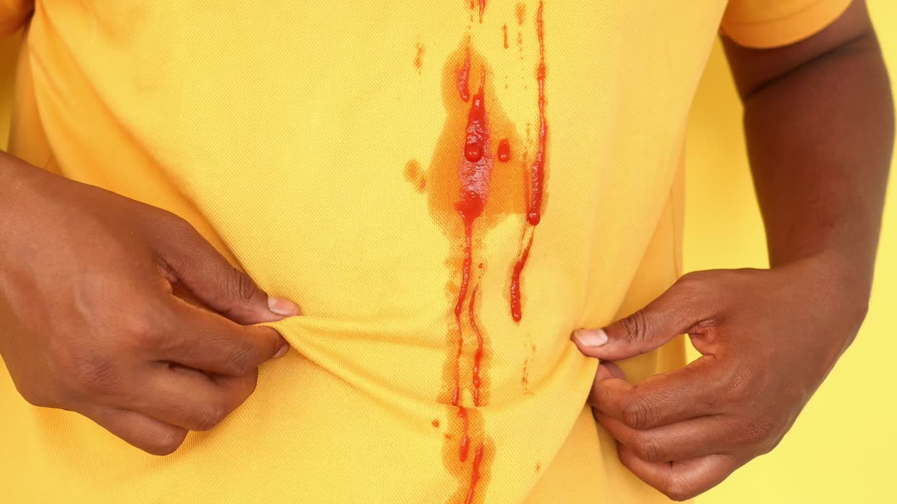 hombre con mancha de ketchup en la camisa amarilla
