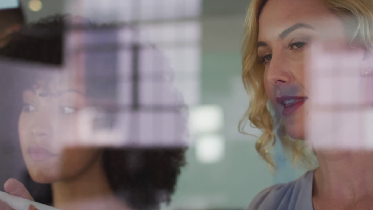 mujeres de negocios diversas en discusión en el trabajo, mujer caucásica escribiendo notas en la pared de vidrio