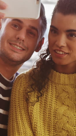 una pareja joven tomando una selfie en la cafetería.