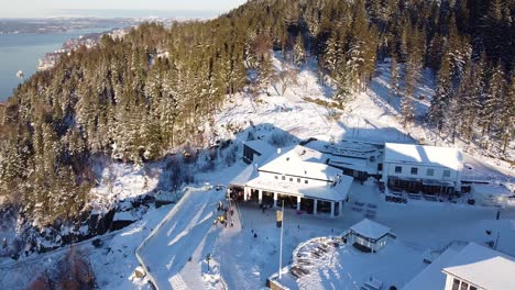 Aerial-backwards-view-over-top-of-the-Floyen-mountain-covered-in-snow---winter-scenery-Bergen