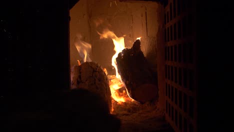 throwing wood into fire in a tile stove