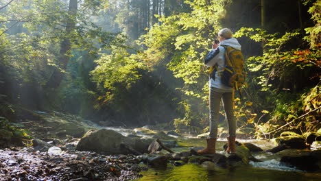 uma fotógrafa tira fotos de uma bela paisagem em uma floresta pitoresca no início do mês