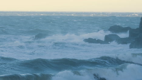 fuertes olas del océano rodando sobre la playa durante la tormenta darragh chocando contra las rocas en ultra cámara lenta creando pulverización del mar. poderoso oleaje turbulento en la bahía británica con clima extremo 4k.